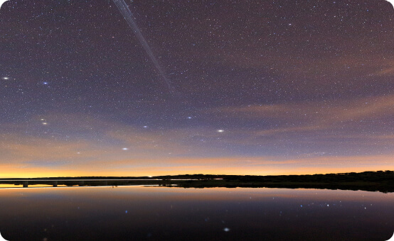 Photo of a starry sky over the top of the water.